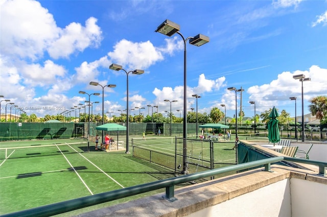 view of community featuring a tennis court and fence