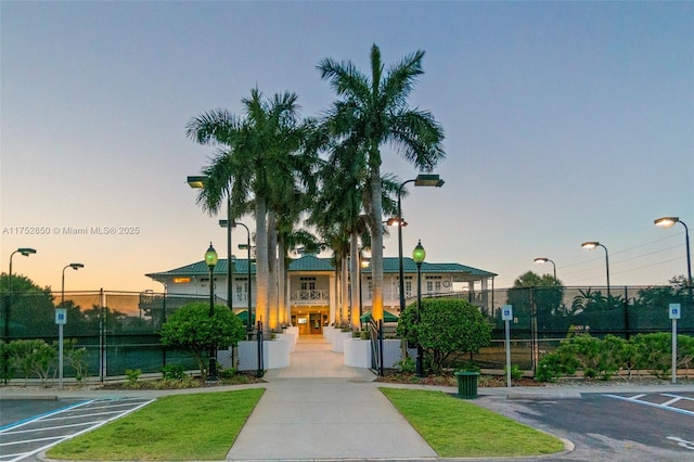 property at dusk featuring uncovered parking and fence