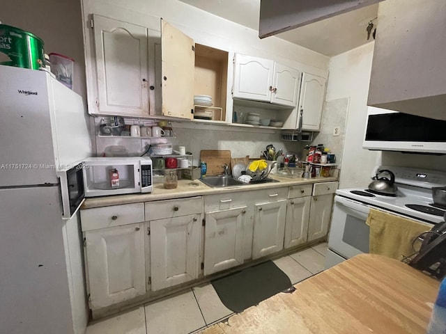 kitchen featuring light tile patterned floors, light countertops, white cabinets, a sink, and white appliances