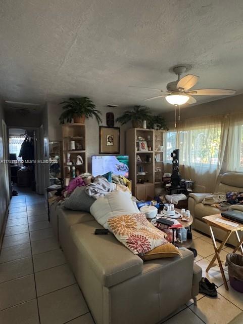 living room with ceiling fan and a textured ceiling