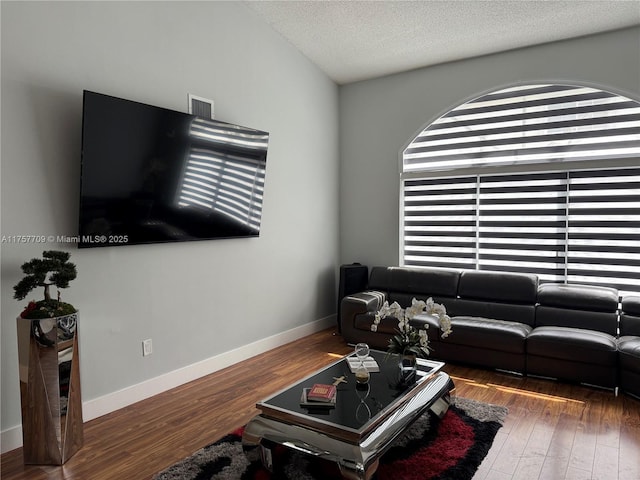 living room with baseboards, a textured ceiling, and hardwood / wood-style floors