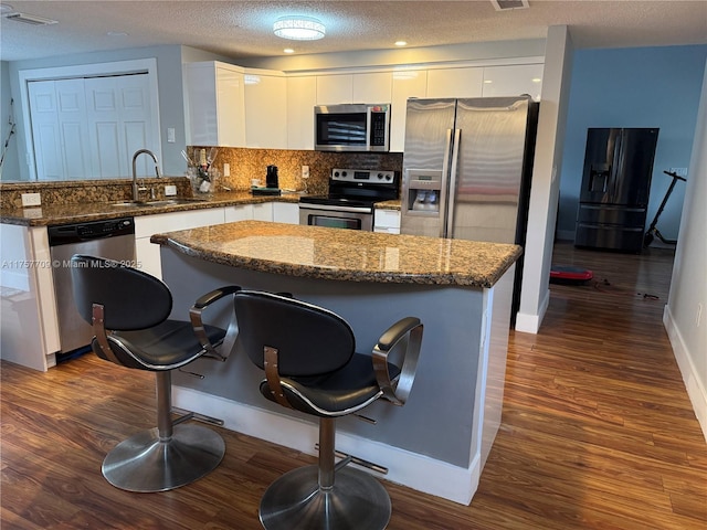 kitchen with dark wood-style floors, appliances with stainless steel finishes, white cabinets, and a sink