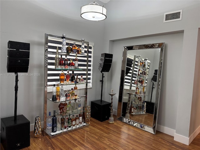 wine cellar with a dry bar, visible vents, and wood finished floors