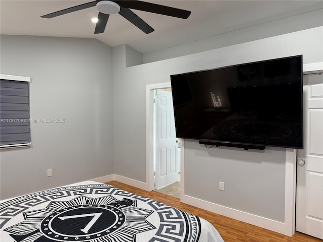 bedroom featuring ceiling fan, light wood-style flooring, baseboards, and vaulted ceiling