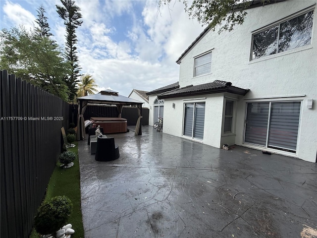 view of patio / terrace with a fenced backyard, a hot tub, and a gazebo