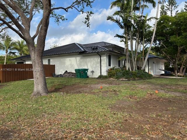 view of property exterior with fence, metal roof, and a yard