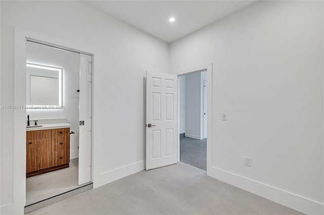 unfurnished bedroom with recessed lighting, concrete flooring, baseboards, and a sink
