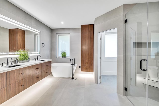 full bath with double vanity, a freestanding tub, a stall shower, and a sink