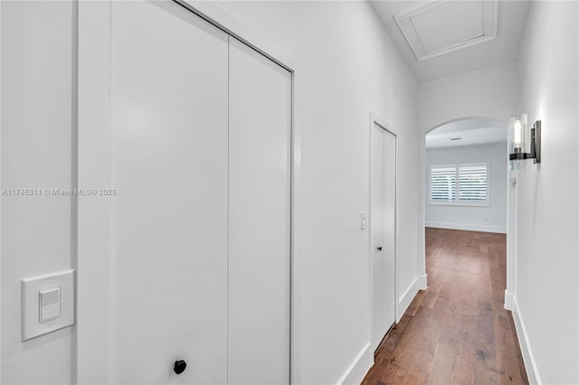 hall with baseboards, arched walkways, and dark wood-style flooring