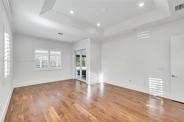 unfurnished room with visible vents, french doors, a raised ceiling, and wood finished floors