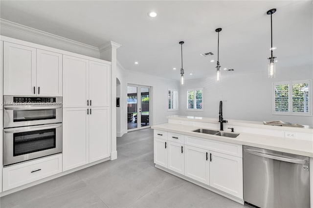 kitchen with visible vents, pendant lighting, a sink, appliances with stainless steel finishes, and crown molding