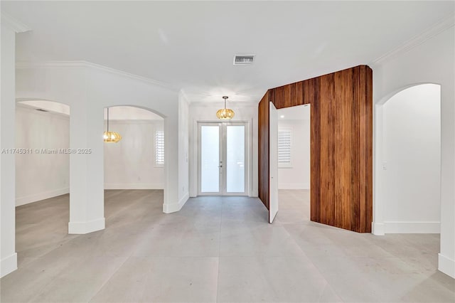 entrance foyer featuring visible vents, arched walkways, ornamental molding, and french doors