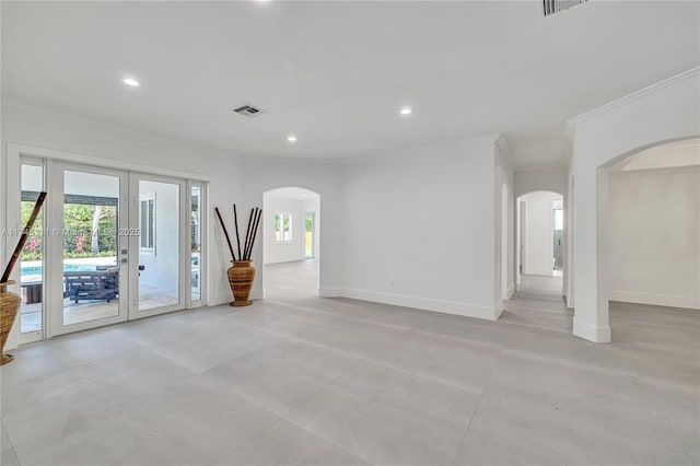 unfurnished living room with arched walkways, a healthy amount of sunlight, french doors, and baseboards