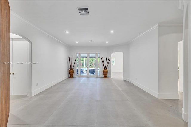spare room featuring visible vents, baseboards, ornamental molding, recessed lighting, and arched walkways