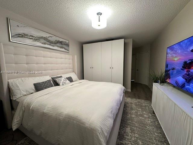 bedroom with dark wood-type flooring and a textured ceiling