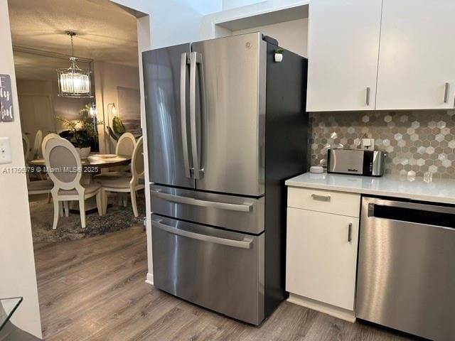 kitchen with stainless steel appliances, light countertops, backsplash, and white cabinetry