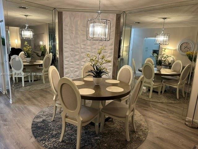 dining area with a chandelier, a textured ceiling, and wood finished floors