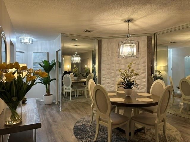 dining area featuring a textured ceiling, visible vents, and wood finished floors