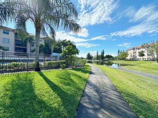 view of home's community featuring a water view, a yard, and fence