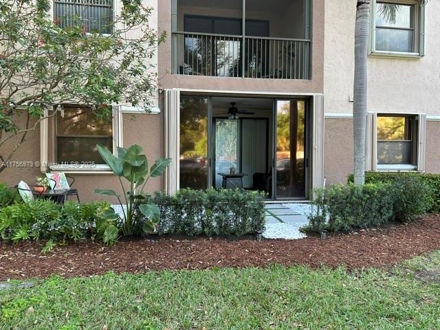 view of exterior entry with a balcony and stucco siding