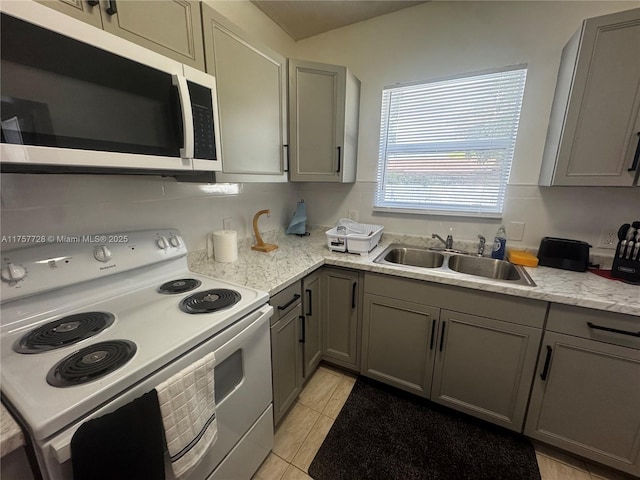 kitchen with a sink, white appliances, light tile patterned floors, and gray cabinets