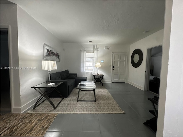 living area with visible vents, baseboards, and a textured ceiling