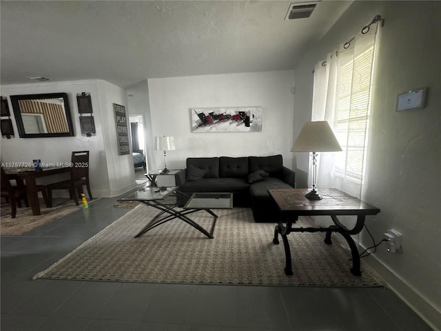 living room featuring visible vents, a textured ceiling, and baseboards