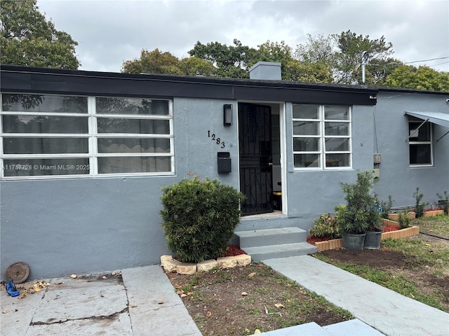 view of front of house featuring a chimney and stucco siding