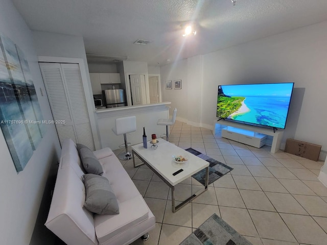 living room featuring light tile patterned flooring, visible vents, and a textured ceiling