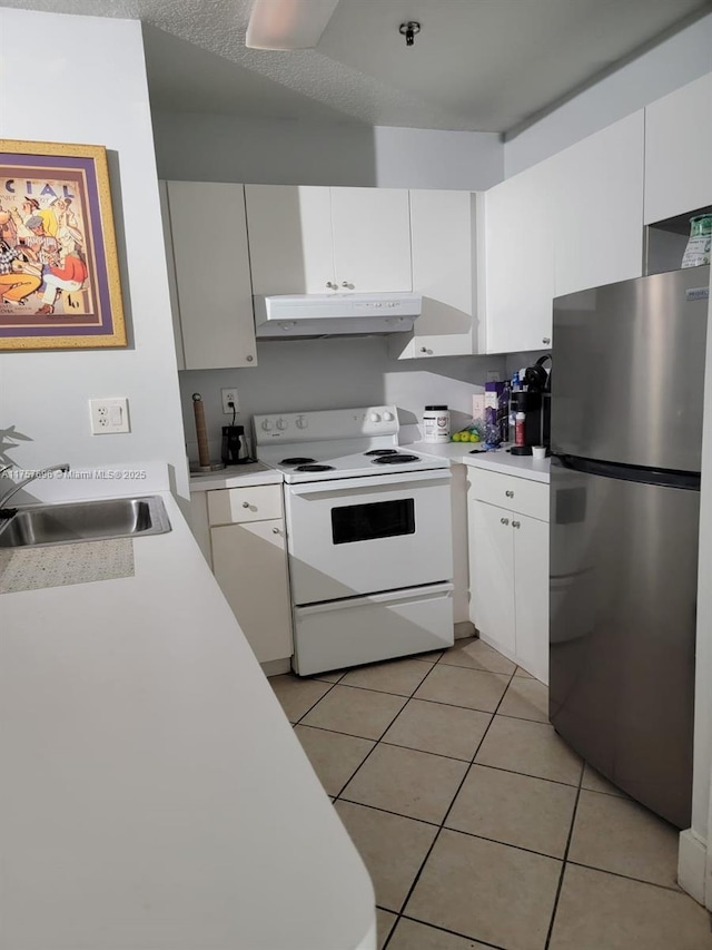 kitchen with under cabinet range hood, light countertops, freestanding refrigerator, white electric stove, and a sink