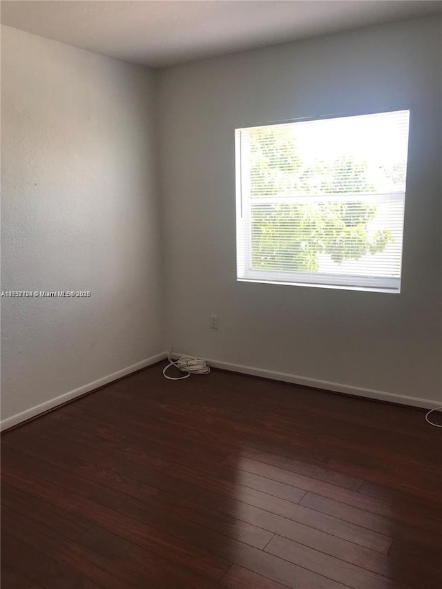 unfurnished room with dark wood finished floors and baseboards