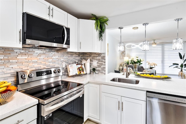 kitchen featuring a sink, white cabinets, appliances with stainless steel finishes, decorative backsplash, and pendant lighting