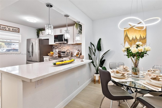 kitchen featuring appliances with stainless steel finishes, white cabinets, backsplash, and pendant lighting