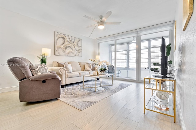 living area with ceiling fan, baseboards, and wood finished floors