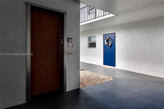 interior space with elevator and a textured wall