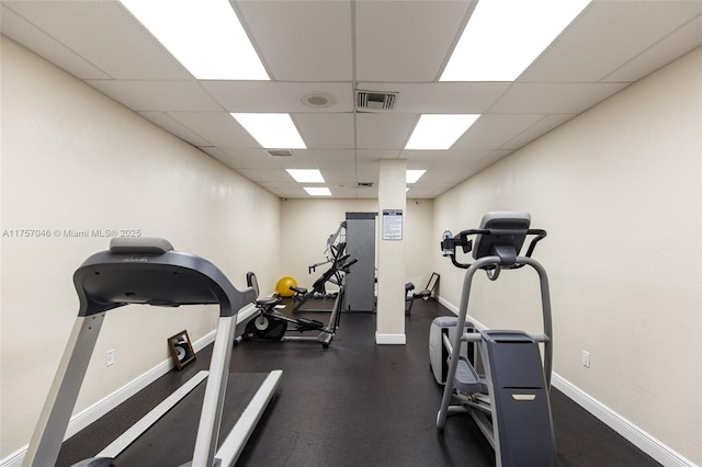 workout area with a paneled ceiling, visible vents, and baseboards