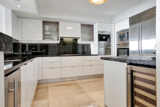 kitchen featuring white cabinets, dark countertops, modern cabinets, wine cooler, and built in appliances