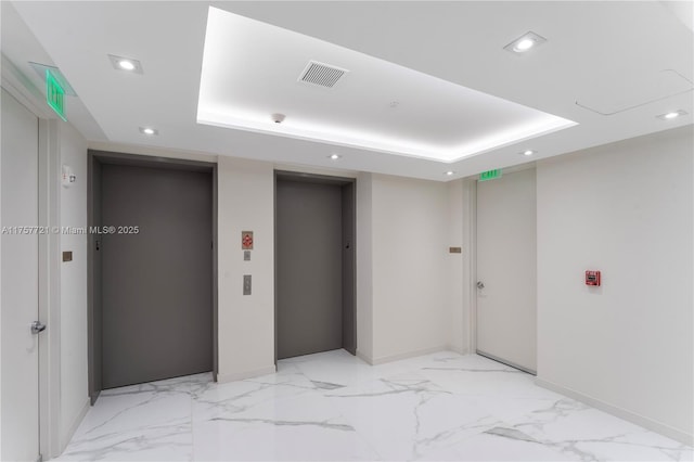 interior space featuring a tray ceiling, elevator, visible vents, and recessed lighting