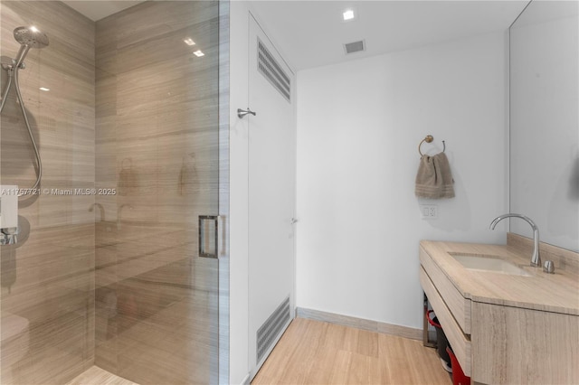 bathroom with vanity, wood finished floors, a shower stall, and visible vents