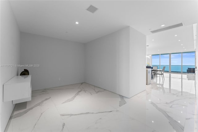 empty room featuring marble finish floor, visible vents, and a wall of windows