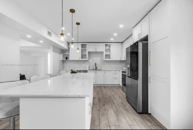 kitchen featuring a breakfast bar, visible vents, backsplash, appliances with stainless steel finishes, and a sink