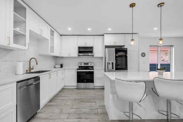 kitchen with stainless steel appliances, tasteful backsplash, glass insert cabinets, a sink, and a kitchen breakfast bar