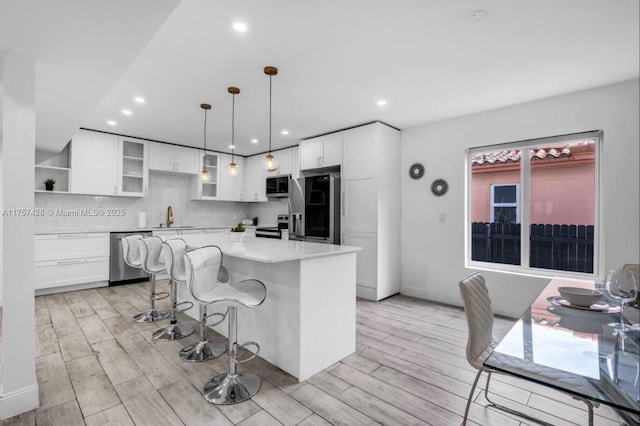 kitchen with tasteful backsplash, glass insert cabinets, appliances with stainless steel finishes, white cabinetry, and a sink