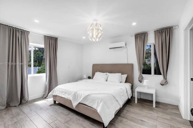 bedroom featuring recessed lighting, light wood-style flooring, baseboards, and a wall mounted air conditioner