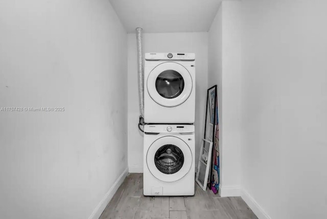 laundry area featuring light wood-type flooring, laundry area, baseboards, and stacked washer / drying machine