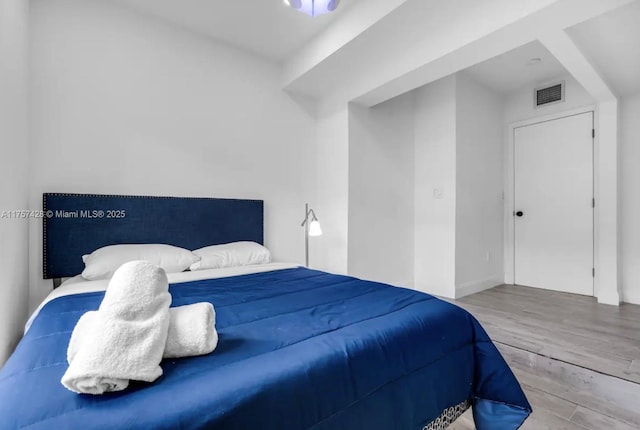 bedroom featuring visible vents and wood finished floors