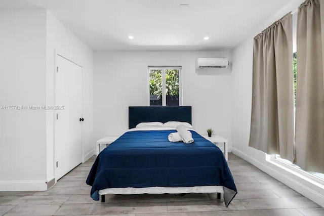 bedroom with light wood-style floors, recessed lighting, baseboards, and a wall mounted AC