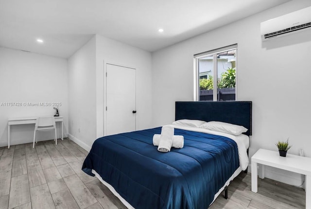 bedroom featuring recessed lighting, baseboards, wood finished floors, and a wall mounted AC