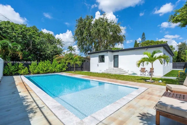 back of house with stucco siding, a patio area, a fenced backyard, and an outdoor pool