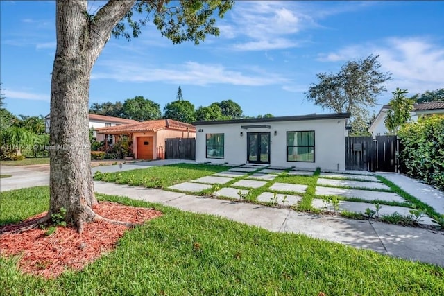 view of front of property with a front yard, french doors, fence, and stucco siding